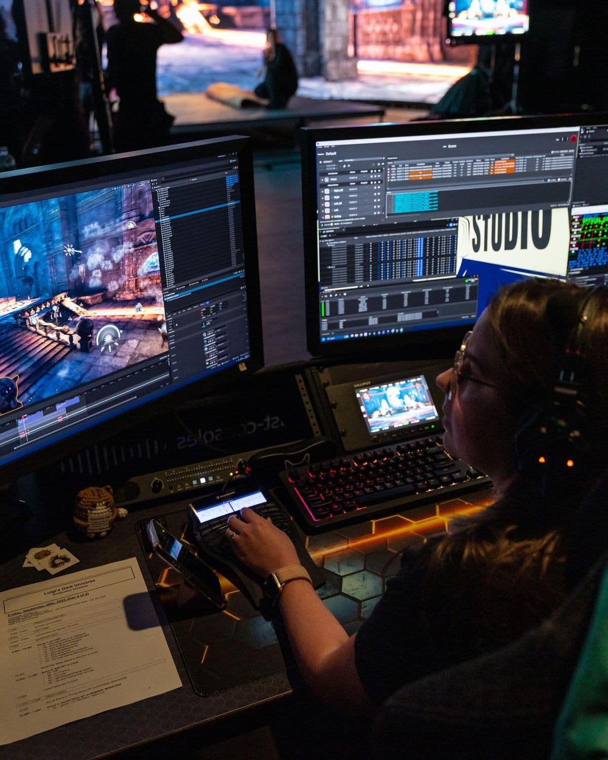 A person editing a game scene across multiple monitors in a production studio