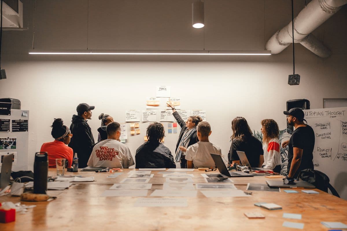 A group reviewing notes and sketches pinned to a wall in a studio